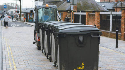 Rear view of electric vehicle towing waste bins at Gloucester Quays, England shallow depth of field...