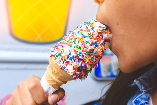 Close up image of girl eating her favorite sweetie cone ice-cream with colourful topping in vintage style 