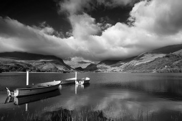 Black and white Landscape image of rowing boats on Llyn Nantlle in Snowdonia at sunset