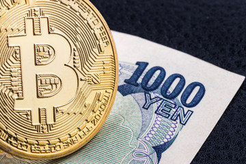 Close-up of a golden bitcoin on 1000 Yen banknote background