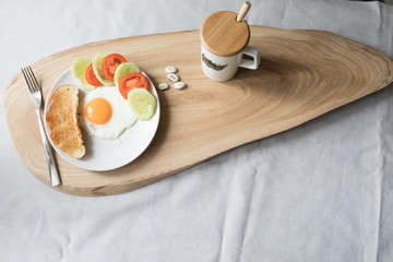 Breakfast with scramble egg tomato toast cucumber on a wood
