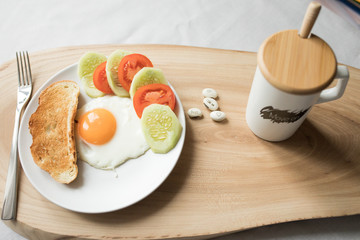 Breakfast with scramble egg tomato toast cucumber on a wood