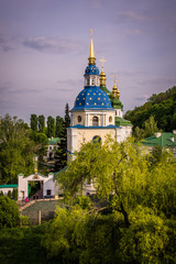 Fototapeta na wymiar Botanical garden with blooming lilac, spring landscape, St. George Cathedral of the Vydubychi Monastery, Kyiv, Ukraine