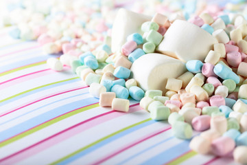 Close up of various marshmallows on a striped background.