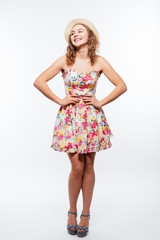 Full length portrait of a cheerful young woman wearing summer clothes while posing and looking at camera isolated over white background