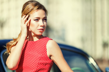 Beautiful young woman in vintage dress with retro auto