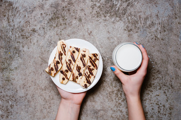 woman hand’s holding bananas dessert with chocolate and glass of milk for breakfast