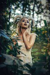 Beautiful model is posing in a forest with white horns 