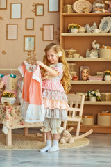 Cute smiling little girl in a vintage dress measure dress from the wardrobe.The style of baby chic.