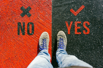 Concept of facing a crucial decision about yes or no shown by shoes on different colored pathways