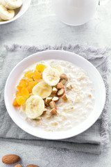 Oats porridge with banana slices, nuts and dried apricot