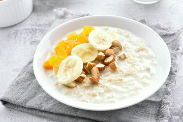 Oats porridge with banana slices, nuts and dried apricot