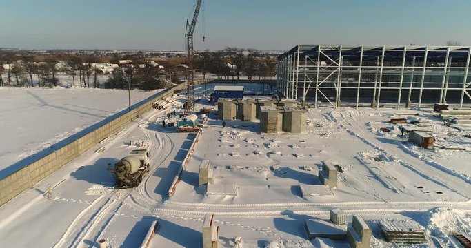 Construction of a modern factory or plant, Industrial area in winter, panoramic view from the air. Modern plant on the snow-covered field, the structural steel structure of a new commercial building
