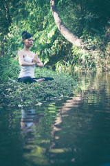 Young woman doing yoga workout outdoor in a creek