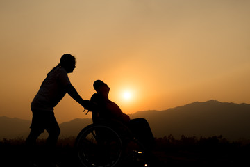 Fototapeta na wymiar Happy boy in wheelchair and sister on sunset. Happy disabled child concept