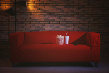 Comfortable couch with popcorn, drink and remote control indoors. Home cinema