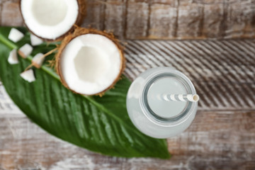 Bottle of coconut water and fresh nuts on wooden table, top view