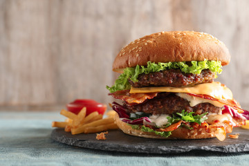 Tasty double burger with bacon on slate plate