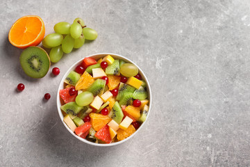 Bowl with fresh fruit salad on grey background