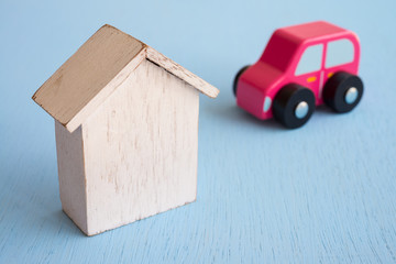 White wooden house and car model on blue pastel background with copy space - Real estate and auto...