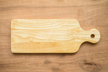 Top view of unused brand new brown handmade wooden cutting board on wooden table background
