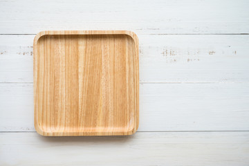 Top view of unused brand new brown handmade wooden dish plate on white wooden table background