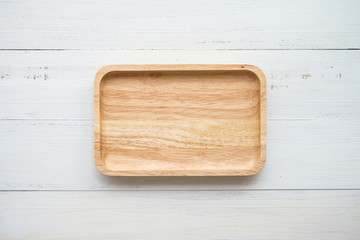 Top view of unused brand new brown handmade wooden dish plate on white wooden table background