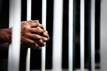 close up of prisoner hands in jail background