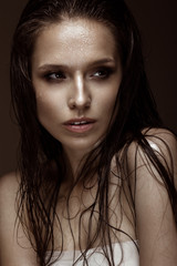 Beautiful girl with a bright make-up and wet hair and skin. Beauty face. Picture taken in the studio on a black background.