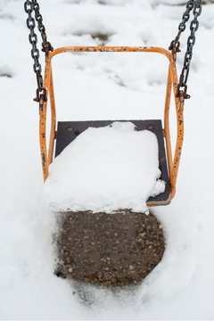 Empty swing in winter time with snow 