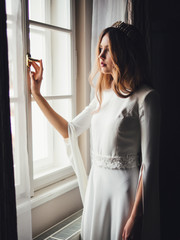 bride near window. white european wedding dress with tiara diadem