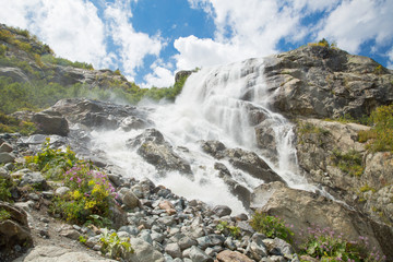 Beautiful waterfall. On a Sunny day the mountain stream flows among the forest . Panorama