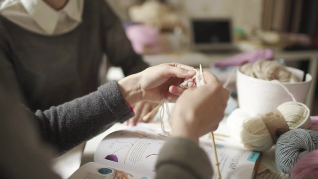 Female hands knitting needles woolen yarn in home. Woman studying to knit clothes from wool yarn in workshop