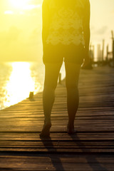 The woman on the wooden bridge to the sea at the beach  during the sunset or sunrise. 