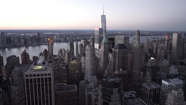 New York City aerial view of Lower Manhattan at dusk, filmed from the East River, featuring the Financial District, Hudson River and Jersey City in the background. 