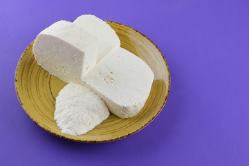 Cheese, Greek cheese on a purple background, feta on a yellow plate, dairy product in the style of minimalism, copy space, top view, milk breakfast, blank for the designer, ultraviolet, art