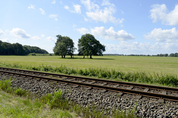 Railway track on the Baltic Sea Island Usedom, Germany, with meadows, trees and blue sky