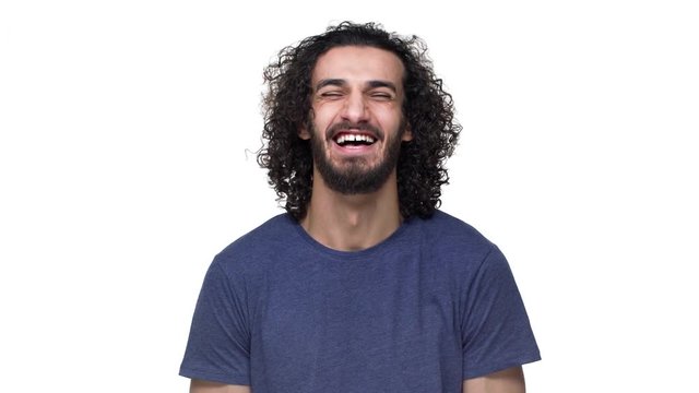 Portrait of young football player with curly hair in casual dark blue t-shirt laughing and expressing joy, isolated over white background. Concept of emotions
