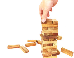 The tower from wooden blocks and man's hand take one block