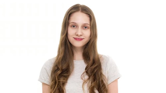 Portrait of affable female model in basic t-shirt looking at camera and smiling positively while nodding and meaning approval, isolated over white background. Concept of emotions