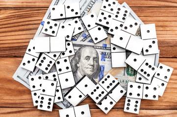 Heap of dominoes with dollar bills on wooden background. Top view.