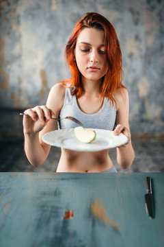Female person against plate with a slice of apple