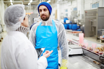 Young man in uniform listening to his colleague explanation of her attitude about working process