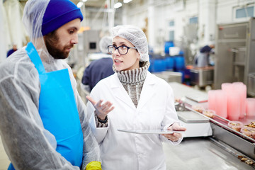 Fish factory expert with touchpad explaining one of workers how to improve working conditions