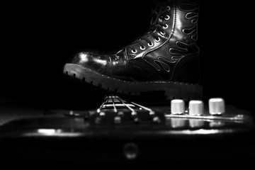 Combat Boot Stepping On A Bass Guitar. Hard Rock and Heavy Metal Concept