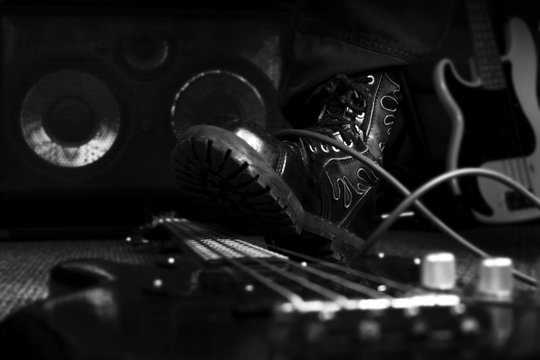 Combat Boot Stepping On A Bass Guitar. Hard Rock and Heavy Metal Concept