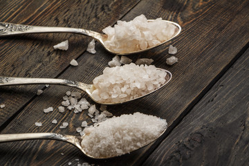 Sea salt on a black decorative antique wooden surface. Background Spa. The concept of the resort. Salt sea for a bath. Sea salt for cosmetic procedures.