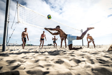 Fototapeta premium Grupa przyjaciół grających w siatkówkę plażową na plaży.