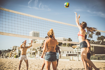 Fototapeta premium Grupa przyjaciół grających w siatkówkę plażową na plaży.