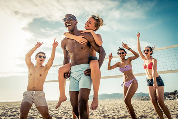Fototapeta premium Grupa przyjaciół grających w siatkówkę plażową na plaży.
